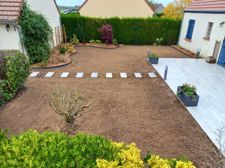 Jardin en cours d'aménagement avec allées en pierres et parterres végétalisés.